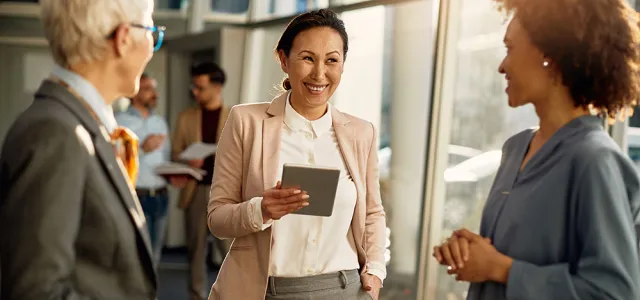 Businesswoman communicating with female colleagues while using digital tablet during the meeting